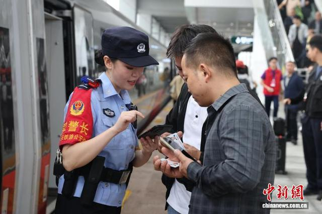 图为乘警在站台上协助乘车旅客。张鑫 摄 