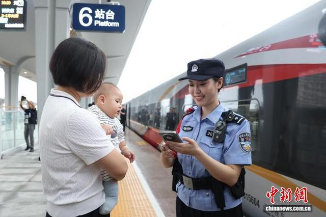 图为乘警在站台上协助乘车旅客。张鑫 摄