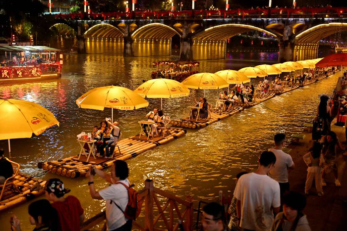 9月25日晚，游客在湖北省宣恩县城贡水河上乘坐“龙游贡水”竹筏赏夜景。新华社图