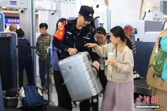 图为民警在安检口帮助旅客。张鑫 摄 