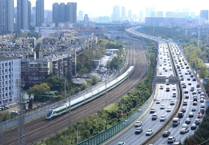 动车组列车行驶在云南昆明城区，一旁的公路上车流不息。新华社发（郑益摄）