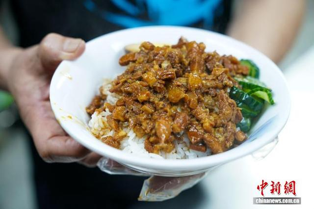 图为9月29日，李兴忠展示他制作的卤肉饭。中新社记者 赵宇航 摄 