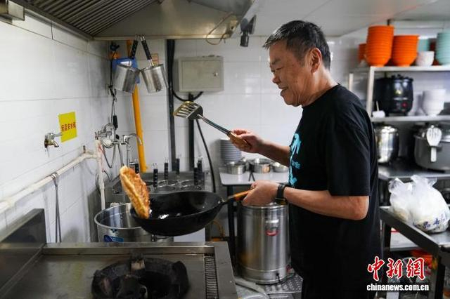 图为9月29日，李兴忠在店内制作菜脯蛋。中新社记者 赵宇航 摄 