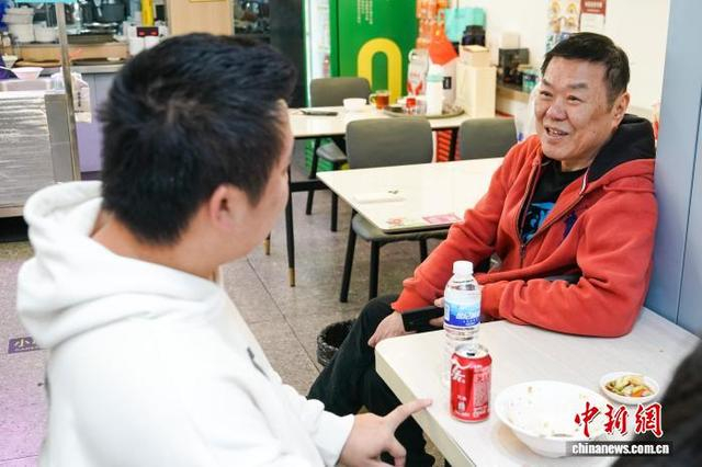 图为9月29日，李兴忠（右）在店内与来自齐齐哈尔的食客交流并询问卤肉饭味道如何。中新社记者 赵宇航 摄 