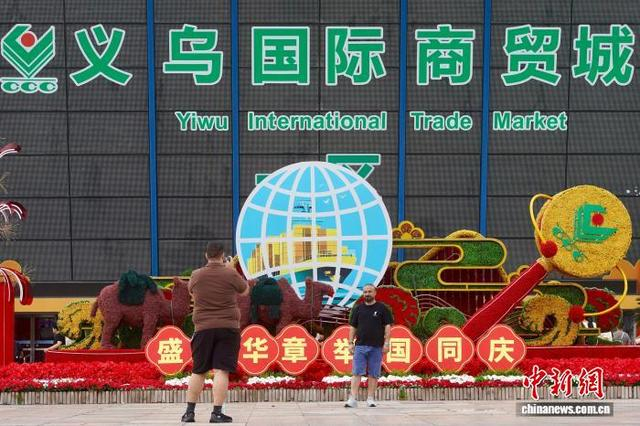 10月1日，在位于浙江的义乌国际商贸城，两位外籍采购商在中国国庆主题装饰前拍照。董易鑫 摄