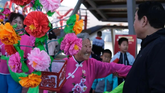 河畔广场，当地老人手持纸花道具参与民俗展演。澎湃新闻记者 林平 图