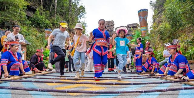 10月3日，游客在广西来宾市金秀瑶族自治县大瑶山盘王界景区体验竹竿舞。 新华社发（高如金 摄）
