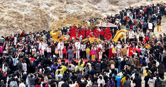 10月3日，游客和工作人员一起在山西吉县黄河壶口瀑布景区合唱《黄河大合唱》（无人机照片）。 新华社发（吕桂明摄）