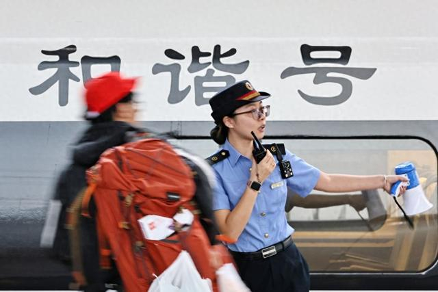 10月1日，在浙江嘉兴南站，工作人员在站台引导旅客有序乘车。新华社发（金鹏 摄）