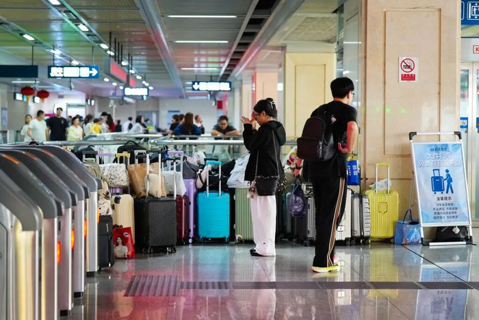 游客将行李存放在地铁6号线江汉路站后拍照。新华社发（产启斗 摄）