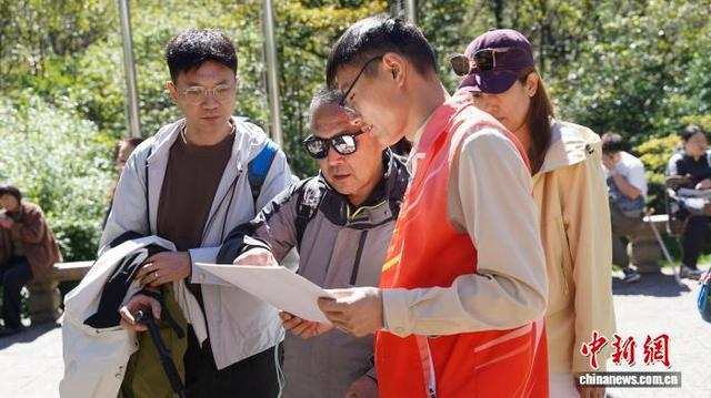 10月7日，黄山迎客松志愿者为游客指引路线。陈璨 摄
