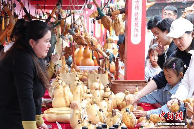 10月17日，山东省聊城市东昌府区，摊主在为顾客讲解“葫芦斜挎包”。 中新社记者 周艺伟 摄