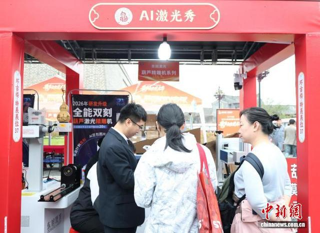 10月17日，山东省聊城市东昌府区，顾客在摊位前体验葫芦激光精雕机AI刻画。 中新社记者 周艺伟 摄