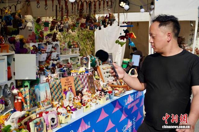10月16日，一名游客在尼泊尔毛毡饰品摊位前拍照。董易鑫 摄