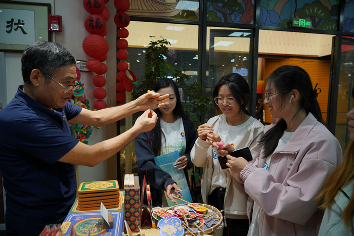 状元工坊店主向同学们展示老北京传统民间玩具“叫猫”。新京报记者 杨得超 摄