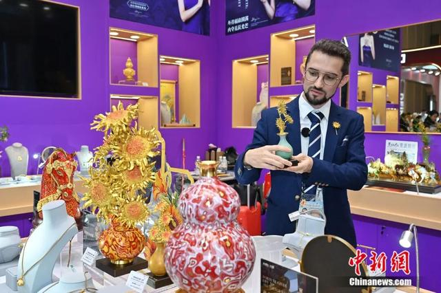 图为境外采购商在时尚饰品展区被一款铜艺品吸引。中新社记者 陈楚红 摄