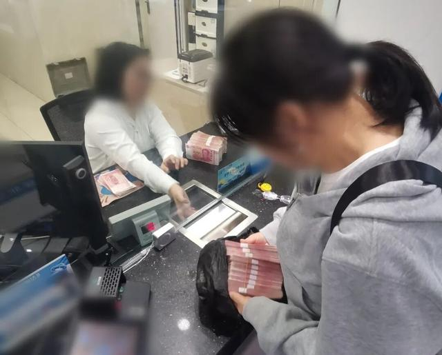 图为民警陪同王女士将40万元现金存回银行。