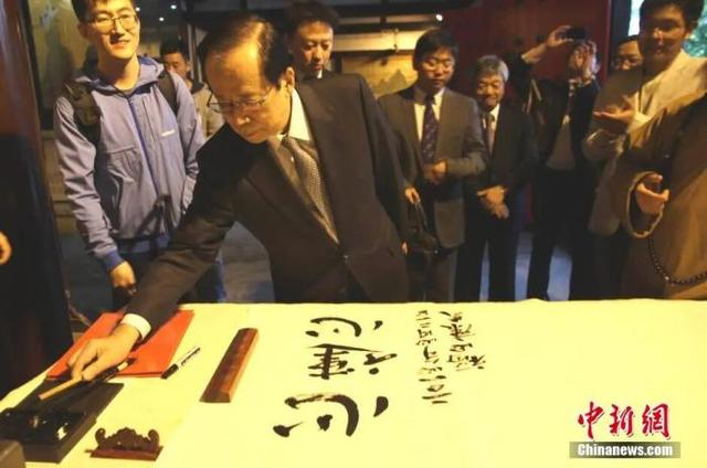 资料图：日本前首相福田康夫参观扬州大明寺鉴真纪念堂，并提笔蘸墨、手书汉字“心连心”。