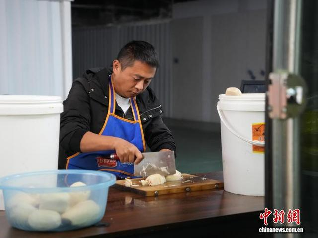 图为10月27日熊泽珲在“爱心厨房”外切当日购买的新鲜莲藕。中新社记者 周燕玲 摄 