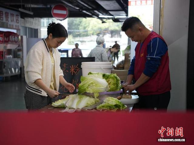 图为10月27日翟饶和一名患者家属在“爱心厨房”外切白菜。中新社记者 周燕玲 摄 