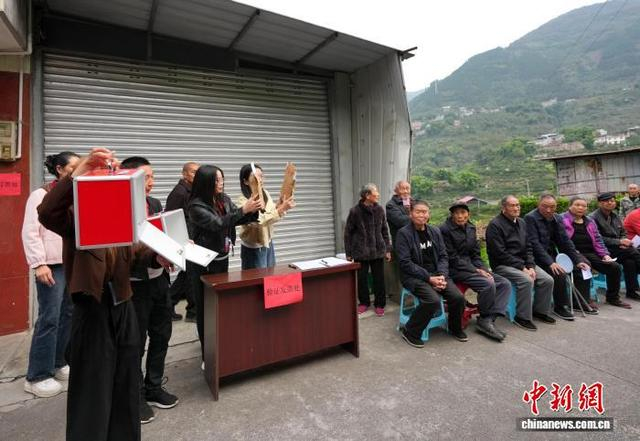 图为工作人员向选民展示选票及投票箱。中新社记者 安源 摄 