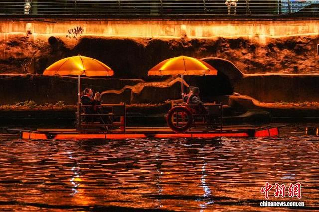 10月30日晚，在湖北省通城县“两河四岸”，灯火映碧波，人潮如织。图为市民游客游览观光。张倩龙 摄