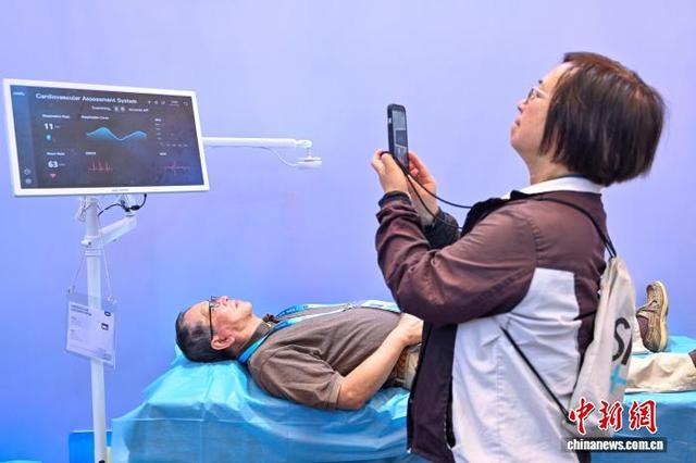 图为境外采购商体验一款非接触心脏健康监测系统。中新社记者 陈骥旻 摄 