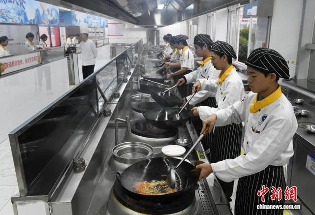 图为在重庆市长江职业培训学校的实训教室里，学员练习炒菜技艺。中新网记者 周毅 摄