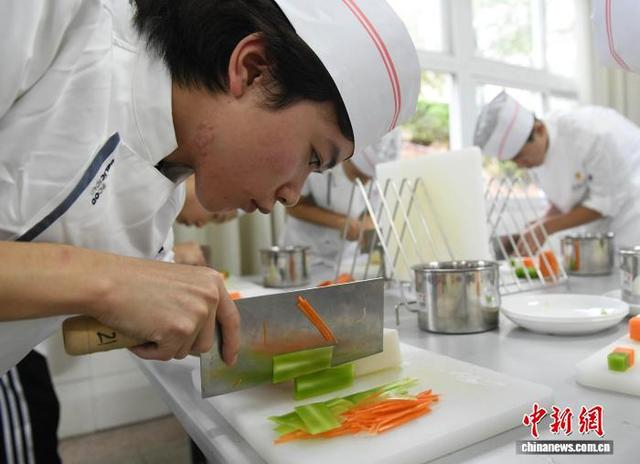 图为在重庆开州区职业教育中心的实训教室里，学员练习刀工。中新网记者 周毅 摄