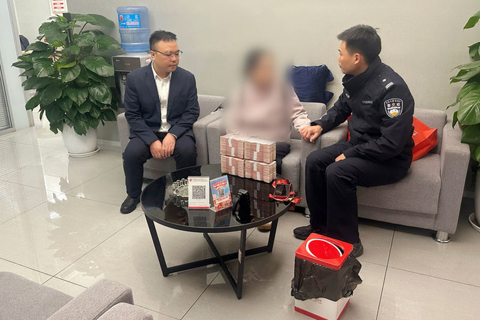覃某某握着民警的手，表示后怕不已，同时对民警和银行员工的及时劝阻表示感谢。重庆警方供图