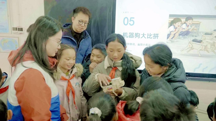 ▲ 青年志愿者指导孩子们制作机器狗模型 摄影：明媚