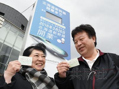 　　3月25日下午，一对夫妇在倒计时牌前高兴地拿出前往东京的北海道新干线首趟列车的车票。（共同社）