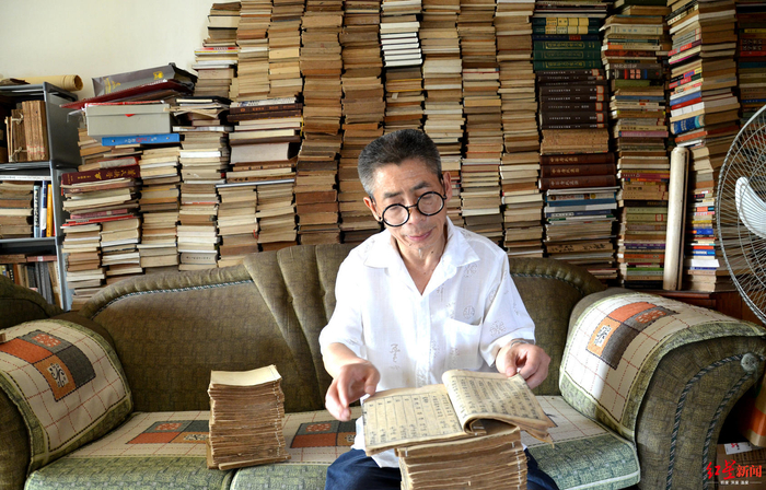  ↑刘国成在家中翻阅藏书