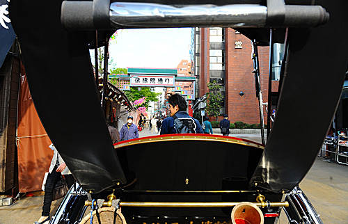  一名人力车夫在日本东京浅草寺寻找生意。（新华社）