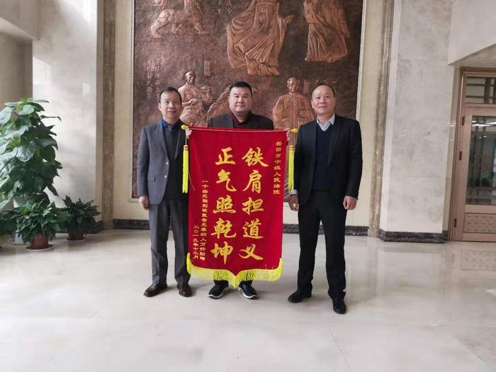  2019年12月19日，万伟勋收到无罪判决生效的裁定后，和律师一起到岳阳中院送锦旗。澎湃新闻记者 谭君 图