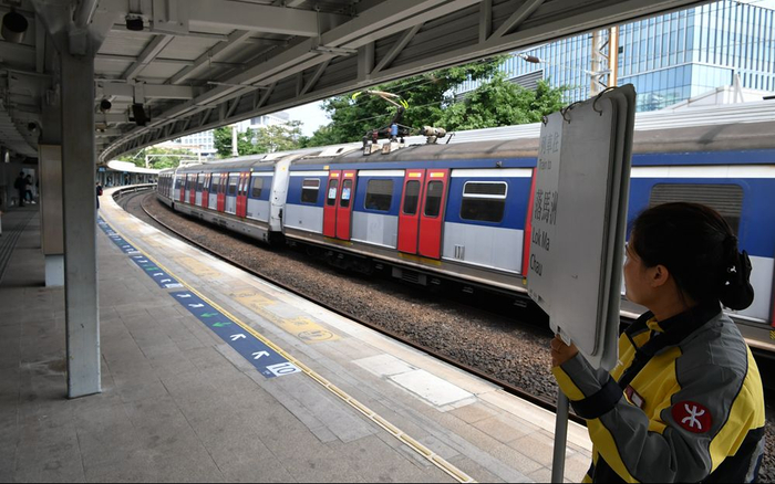  12月21日上午，一名港铁工作人员在大学站站台举着指引牌引导乘客。