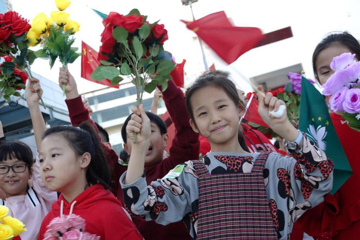 △12月18日，澳门中小学师生在机场欢迎习近平主席的到来，这是教业中学国际部P5C班学生朱玥（左）、P4A班学生张博琳（右）在欢迎的人群中。