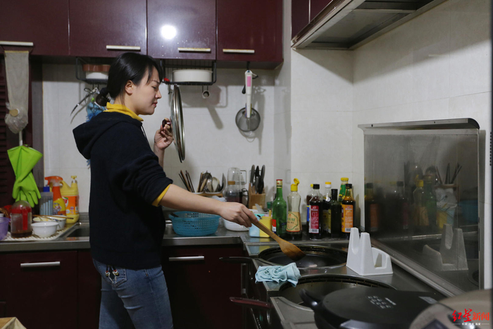 ▲&nbsp;薛春艳用锅盖挡脸，以免被热油溅到。
