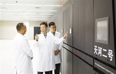  图④ 国防科技大学计算机学院计算机研究所所长肖立权（中）与团队成员在“天河二号”高性能计算机机房讨论。新华社发