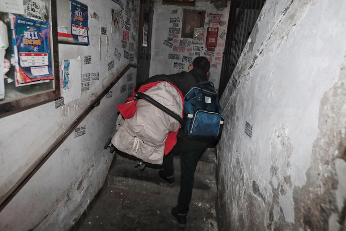 　　12月11日，朝阳区三丰里，一栋没有电梯的居民楼里，一居民背着背包，抱着小推车步行走上楼梯。新京报记者 王嘉宁 摄