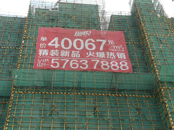 图为绿庭尚城璟悦在建住宅楼，多幅“单价40067元/平方米精装新品火爆热销”的巨幅广告围绕在其周围，颇为显眼。方超/摄影