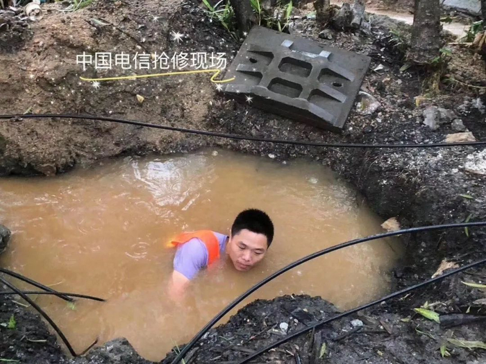 ▲抢修人员跳入灌水的井中布放光缆