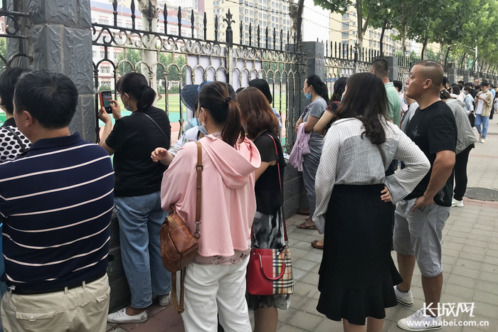 考生进场后，家长也并未早早地离去，此刻，他们在“并肩作战”。实习记者李珊珊 摄