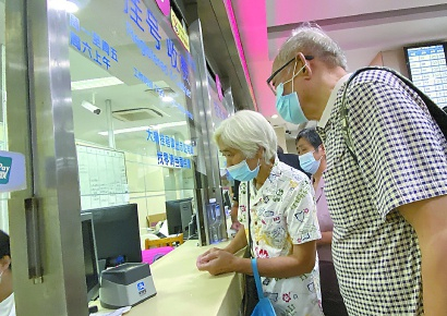 两名老年患者在人工窗口前排队挂号。张驰摄