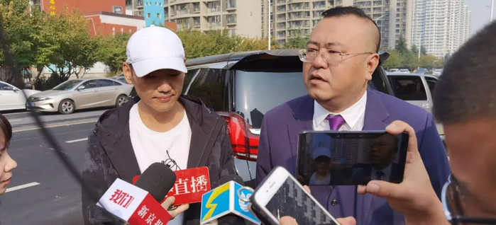  今日上午，张志超（左）和代理律师李逊（右）在法院外接受媒体采访。图/受访者提供