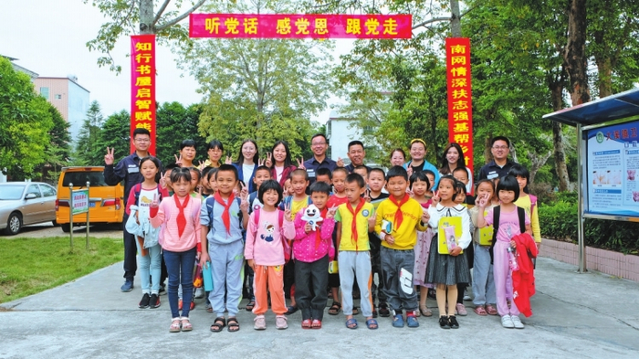 扶贫干部和记者团参观完“南网知行”书屋后，在井美村中心小学和学生们合影。 林梓博 摄