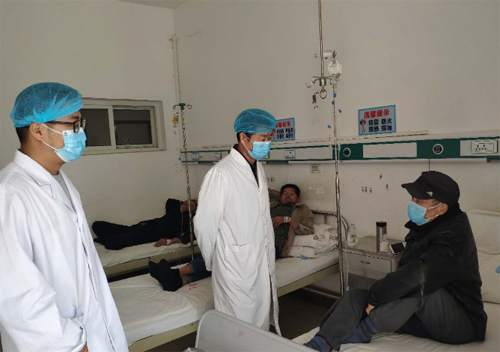 图为陈春阳（中）和医务人员在住院病房了解贫困户身体情况
