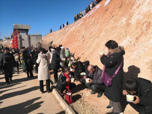在“冬至民俗文化庙会”广场上吃“牛娃子饭”的乡亲们。