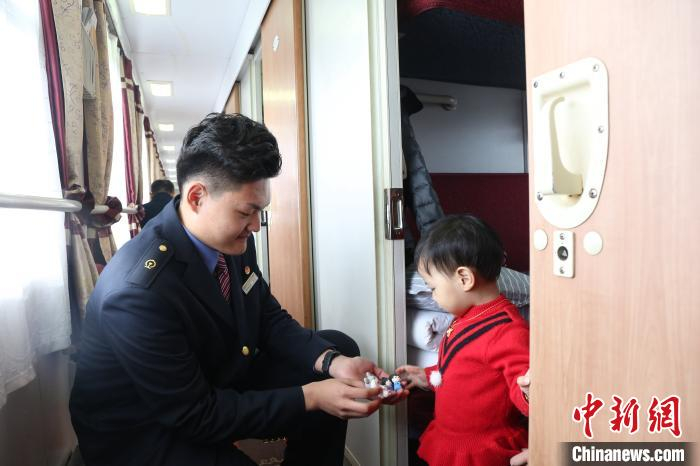  乘务人员捏制卡通吉祥物，送给乘车小旅客。　方正 摄