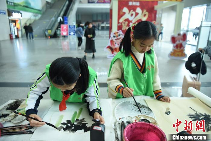 六名小学生现场书写国画赠送旅客。　庄建华 摄